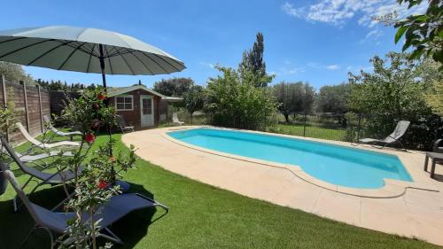 a swimming pool in a yard with an umbrella at Mas Sansonnets in Mouriès