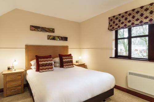 a bedroom with a large white bed and a window at 2 Bedroom Lake District Cottage At Windermere Marina Village in Bowness-on-Windermere