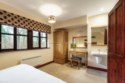a bathroom with a bed and a sink and a mirror at 2 Bedroom Lake District Cottage At Windermere Marina Village in Bowness-on-Windermere