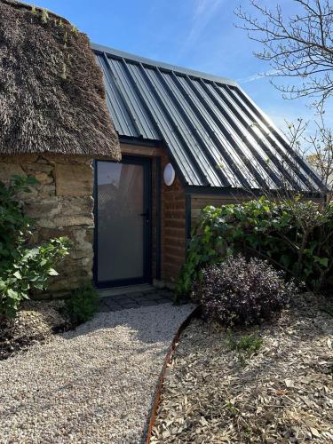 a small building with a thatch roof and a door at La Mare aux Oiseaux, The Originals Collection in Saint-Joachim
