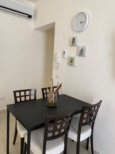 a dining room table with chairs and a clock on the wall at Le Buguse suite apartment in Lecce