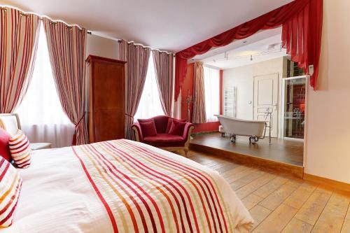 a bedroom with a bed and a chair and a tub at Champagne Domaine Sacret - AY in Épernay