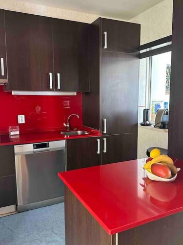 a kitchen with a red counter top with a bowl of fruit at Apartamento Praia do Pedrogão com vista mar in Leiria