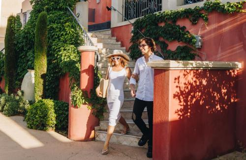 a man and a woman walking down the street at Hôtel Liberata & Spa in LʼÎle-Rousse