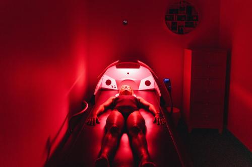 a person laying in a bed in a red room at Hôtel Liberata & Spa in LʼÎle-Rousse