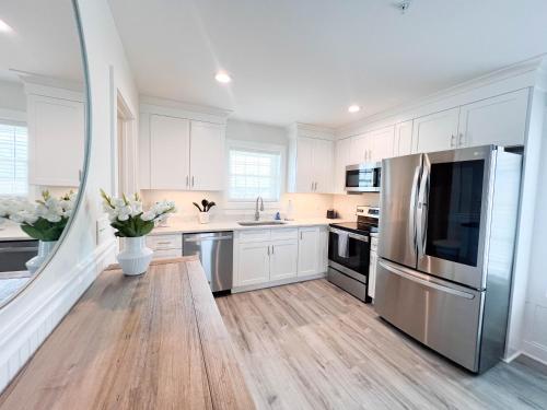 a kitchen with white cabinets and a stainless steel refrigerator at 1001 King ADA Suite, 1st Floor Serenity in Surf City