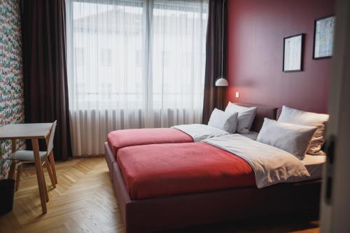 a bedroom with a bed with a red blanket and a window at The Circus Apartments in Berlin