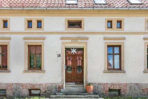 a white building with a wooden door and stairs at Ferienwohnung mit großem Garten in Klosterheide