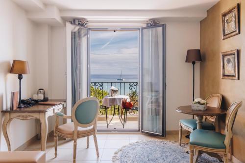 a living room with a table and a view of the ocean at Hôtel Liberata & Spa in LʼÎle-Rousse