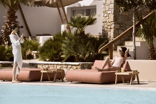 two women standing next to a swimming pool at Ethereum Mykonos in Mýkonos City