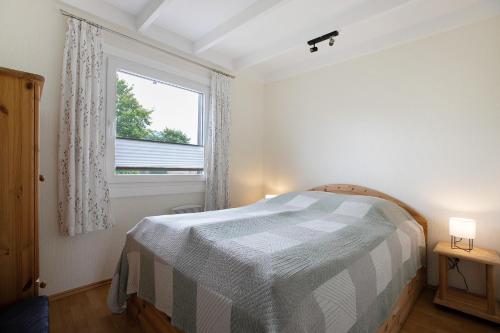 a white bedroom with a bed and a window at Ferienhaus Drybarg in Simonsberg
