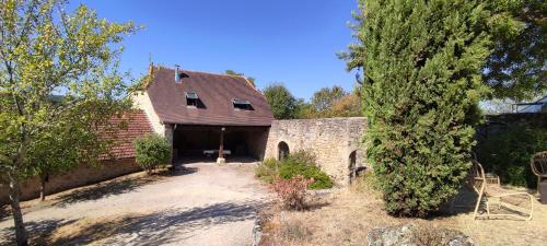 un vieux bâtiment en briques avec un garage dans une cour dans l'établissement Quercynoise de Charme Piscine et vue sur Vallée du LOT, à Balaguier-dʼOlt