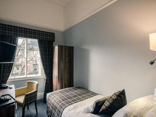 a hotel room with a bed and a desk and a window at Royal West End Hotel in Glasgow