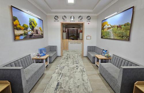 a waiting room with couches and tables and posters at Hostel DANEXAN APA in Nukus