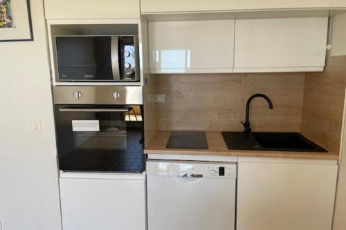 une cuisine avec des armoires blanches, un évier et un micro-ondes dans l'établissement Studio in residence - sea view, au Golfe-Juan