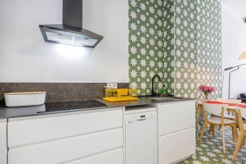 a kitchen with white cabinets and a sink at Artisan Haven: El Cabanyal Oasis in Valencia