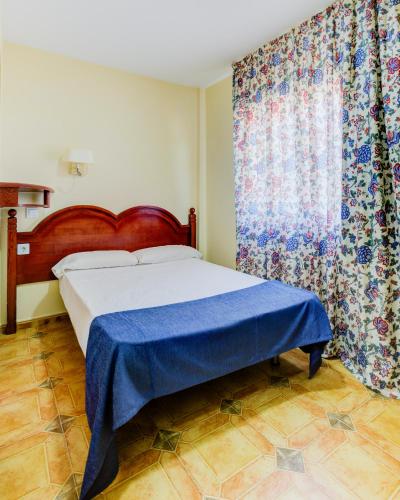 a bedroom with a bed with a blue blanket and a window at Hotel Pizarro in Humanes de Madrid