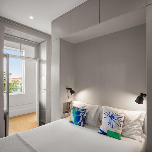 a bedroom with a large white bed and a window at Baumhaus Serviced Living - Art & Design Apartments in Porto