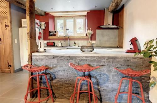 une cuisine avec tabourets rouges en face d'un comptoir dans l'établissement La Grange de Papi Elie, à Sireix