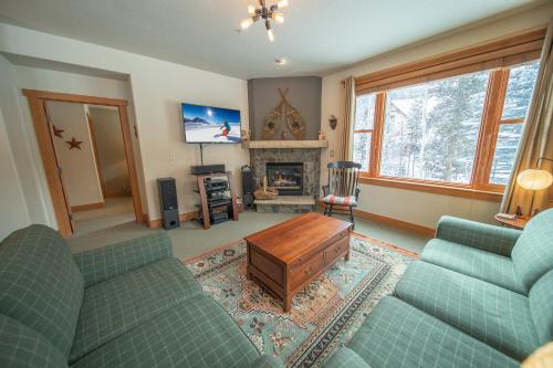 a living room with two green couches and a fireplace at Red Hawk Townhomes 2333 by SummitCove Lodging in Keystone