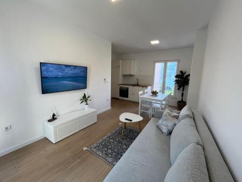 a living room with a gray couch and a kitchen at Apartments Laura in Korčula