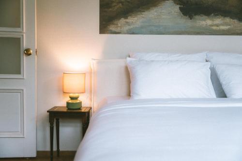 a bedroom with a white bed with a lamp on a table at Vila Šilelis in Palanga