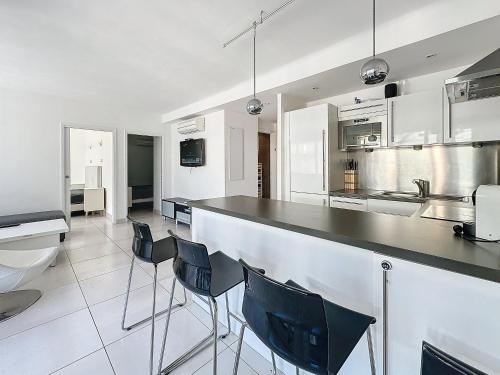- une cuisine avec un comptoir et des chaises dans l'établissement 57m2 - 2 chambres, terrasse, Croisette-Martinez, à Cannes