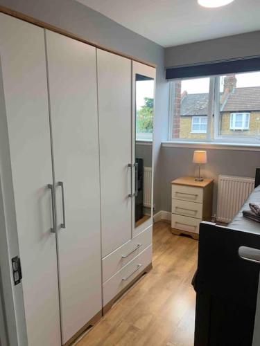 a bedroom with white cabinets and a desk and a window at 2 Bed Apartment, Southgate, London in East Barnet