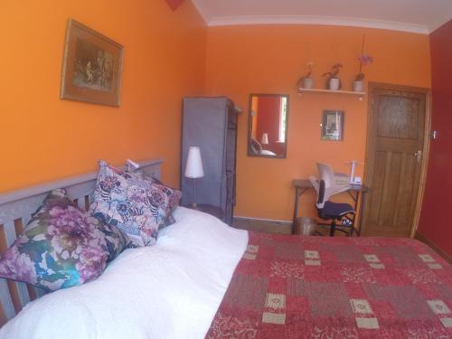 a bedroom with orange walls and a bed and a desk at Carlton Mansions - The Red Room in Bristol
