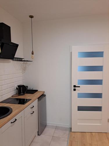 a kitchen with white cabinets and a blue and white door at BOOGIE Home Kamienica Łódzka in Łódź