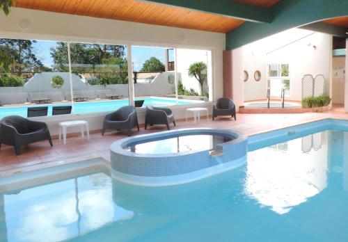 - une piscine avec des chaises et une table à côté de la piscine dans l'établissement Hotel L'Oceane, à La Cotinière