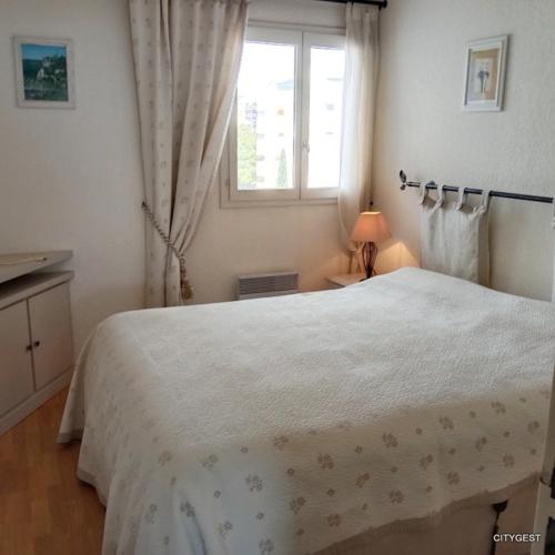 une chambre avec un grand lit blanc avec une fenêtre dans l'établissement Appartement T2 vue Mer, moderne classé 3 etoiles Parking 4ROSE326, à Canet