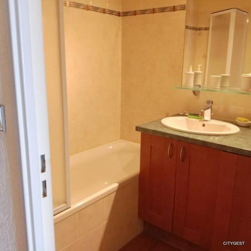 une salle de bain avec un lavabo et une baignoire et un lavabo dans l'établissement Appartement T2 vue Mer, moderne classé 3 etoiles Parking 4ROSE326, à Canet