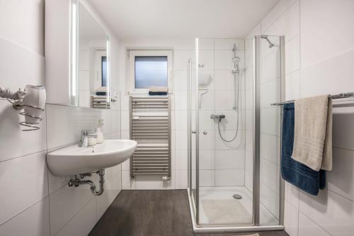 ein weißes Badezimmer mit Waschbecken und Dusche in der Unterkunft He, wat mooi in Lübeck