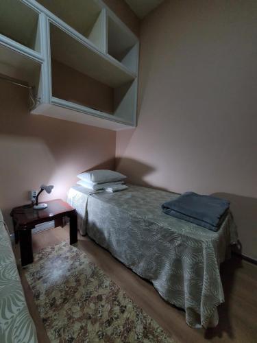 a bedroom with a bed and a night stand with a table at Kzazendf Cama&Cafe Hospedagem Familiar in Brasilia
