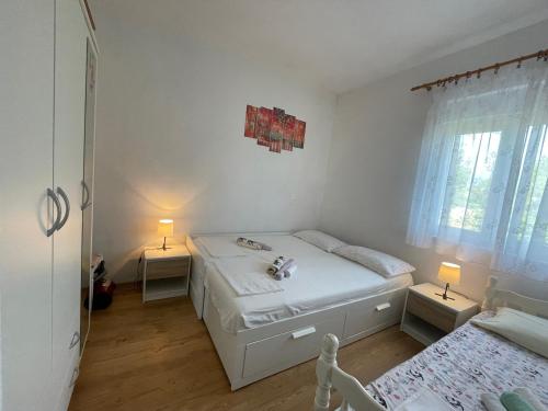 a white bedroom with two beds and two lamps at Kuća za odmor Lara in Kaštela