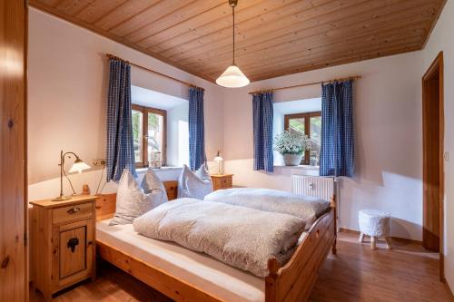 a bedroom with a large bed with blue curtains at Ferienwohnungen „Zum Bauern“ in Oberaudorf