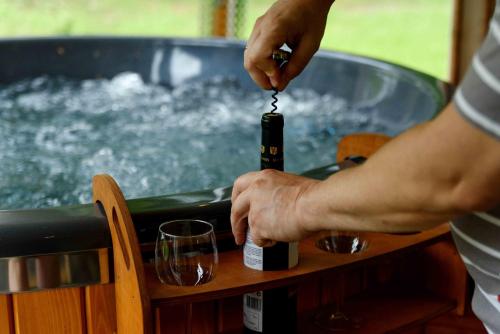 a person pouring a glass of wine into a hot tub at Tylawa - Domki w Beskidzie Niskim in Tylawa