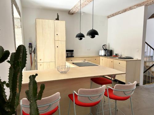 une cuisine avec une grande île et des chaises rouges dans l'établissement Maison avec patio et spa centre ville, à Narbonne