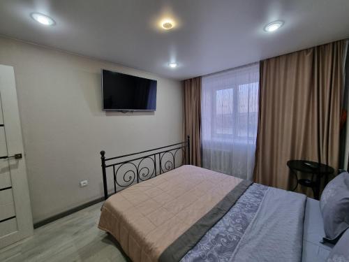 a bedroom with a bed and a flat screen tv at Набережная Иртыша с красивым видом на реку in Ustʼ-Kamenogorsk