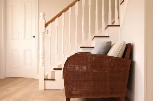 a wicker chair in a hallway with stairs at Luxury Pet-Friendly Retreat with Private Hot Tub in Boardmills