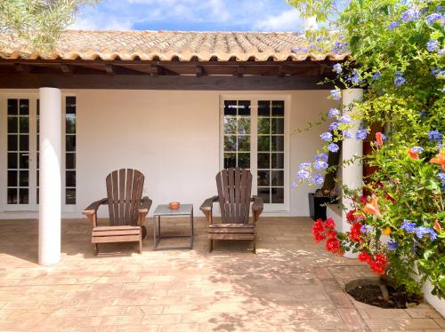 two chairs and a table on a patio with flowers at Casinha Serena by east ALgarve guest in Santo Estêvão