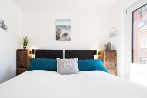 a bedroom with a large white bed with blue pillows at Paddel Nr 5 in Neustadt in Holstein