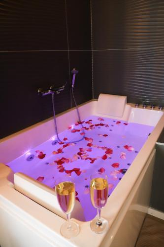 - une baignoire avec deux verres de vin dans l'établissement SUITE Serenity Room SPA- Balnéothérapie, à Saint-Étienne