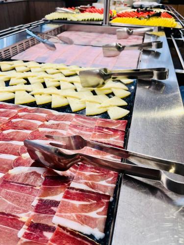 a bunch of food on a table with tongs and meat at Hotel Condestable Iranzo in Jaén