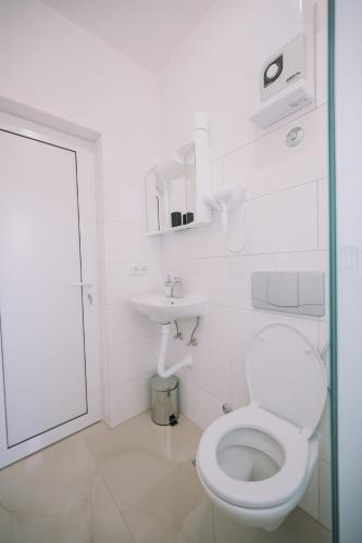 a white bathroom with a toilet and a sink at Apartments Leandra in Ulcinj