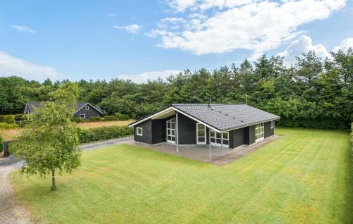 a small black house in a field with a yard at 3 Bedroom Beautiful Home In Hovborg in Hovborg