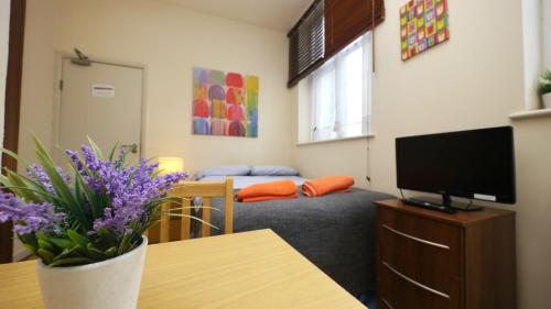 a living room with a couch and a table with purple flowers at Studio 47B in London