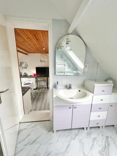 une salle de bain blanche avec un lavabo et un miroir dans l'établissement Les Landelles, à Saint-Lunaire