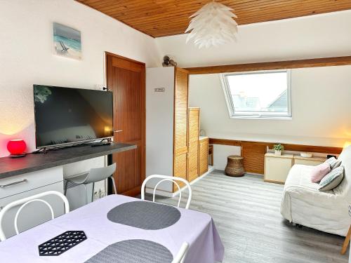 - un salon avec une table et une télévision dans l'établissement Les Landelles, à Saint-Lunaire